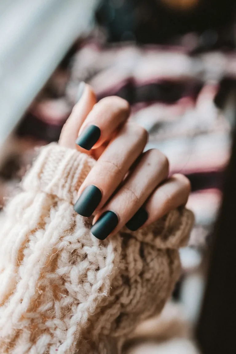 Matte forest green nails on a cream knit