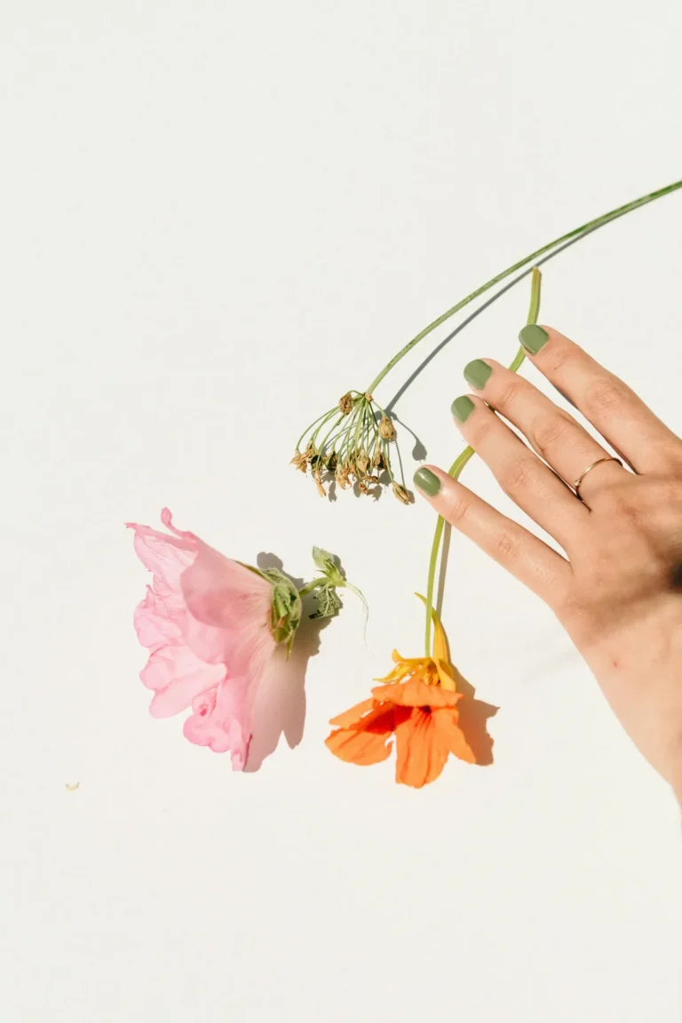 Sage green nails beside dried flowers