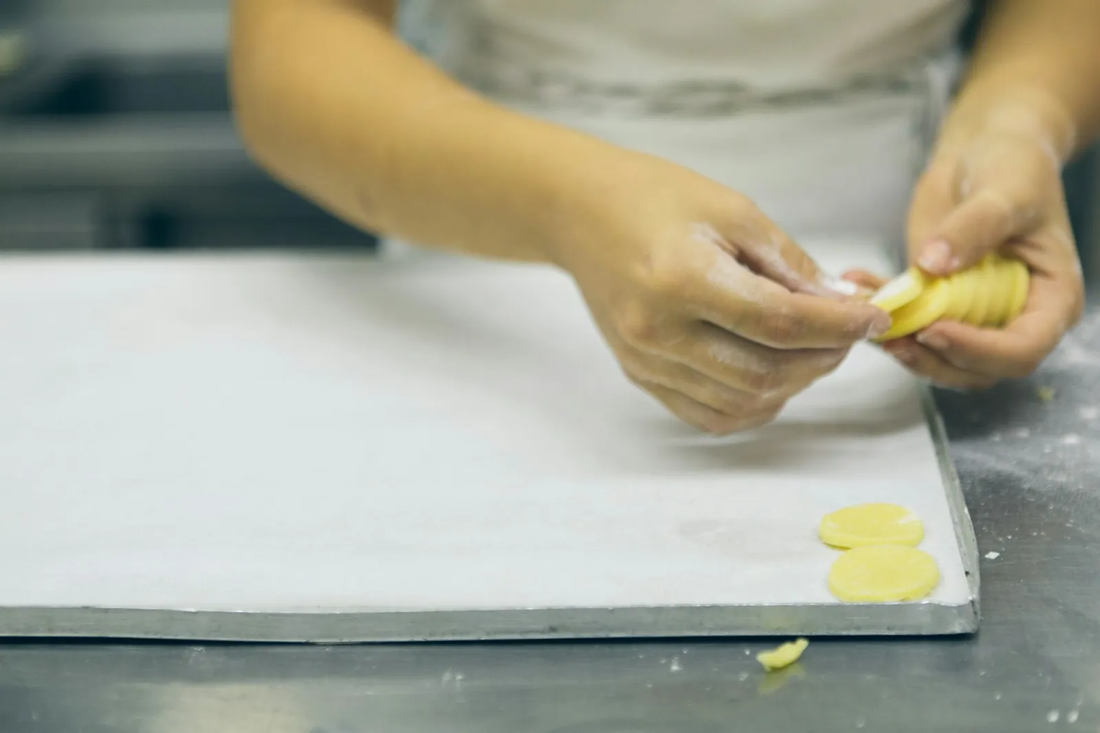 Hands folding pasta on a tray