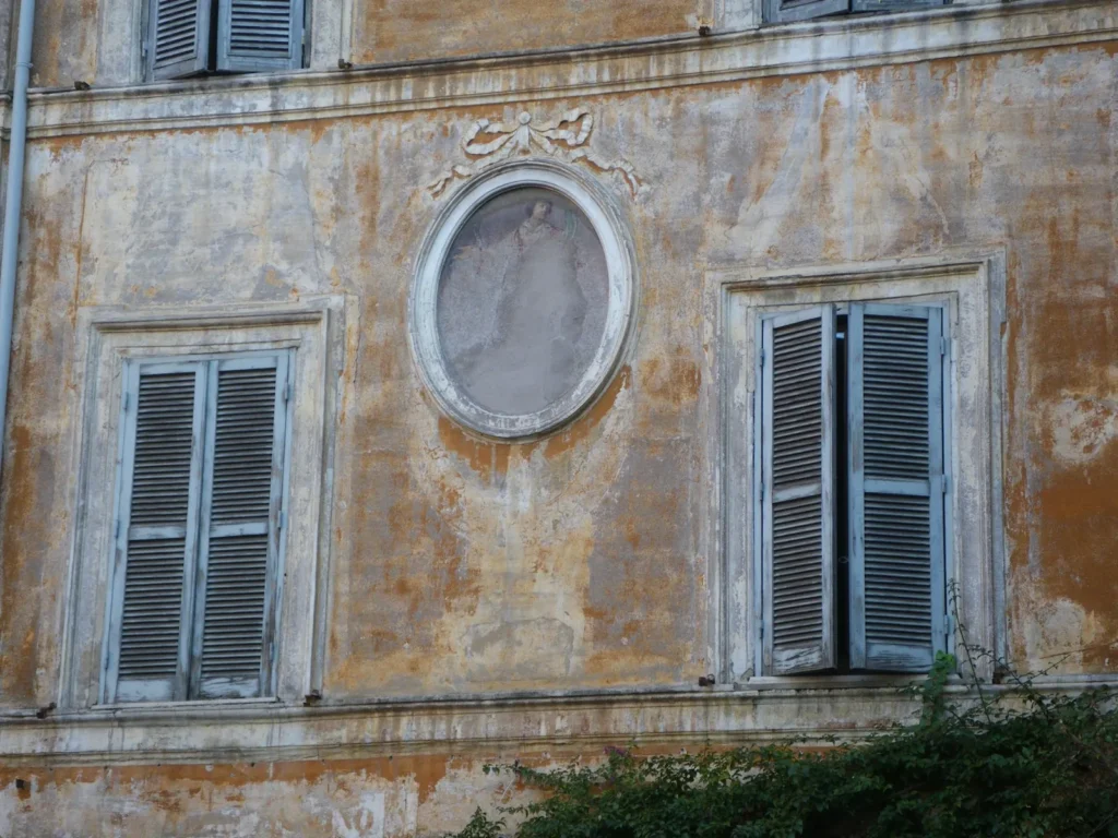 Old facade with green shutters and a stone medallion
