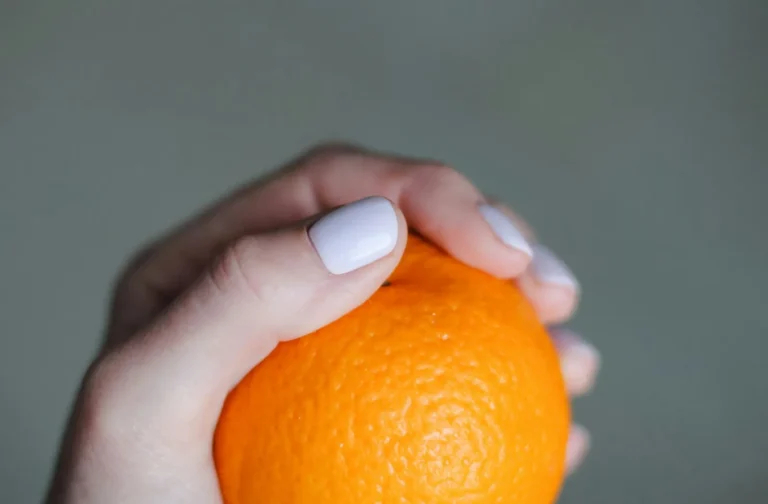 White nails holding an orange