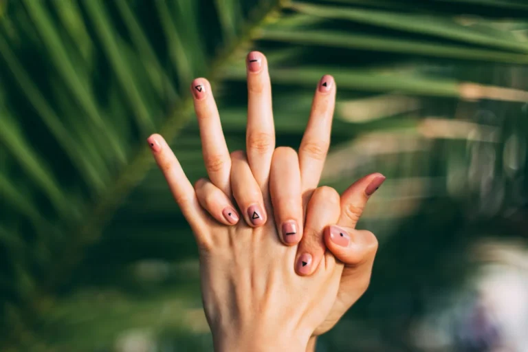 Hands with painted nails among palm leaves