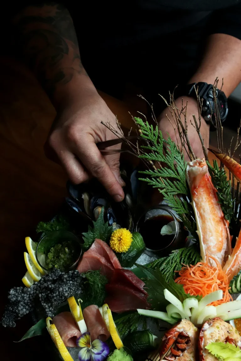 Plating a sashimi platter with herbs and flowers