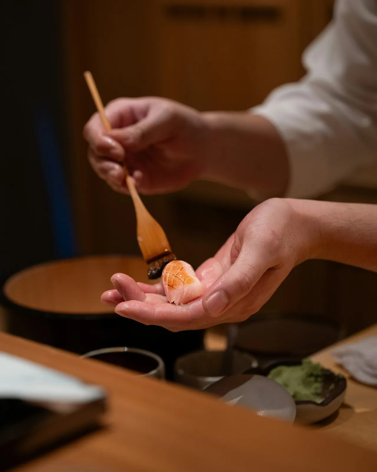 Chef brushing soy glaze onto a piece of nigiri