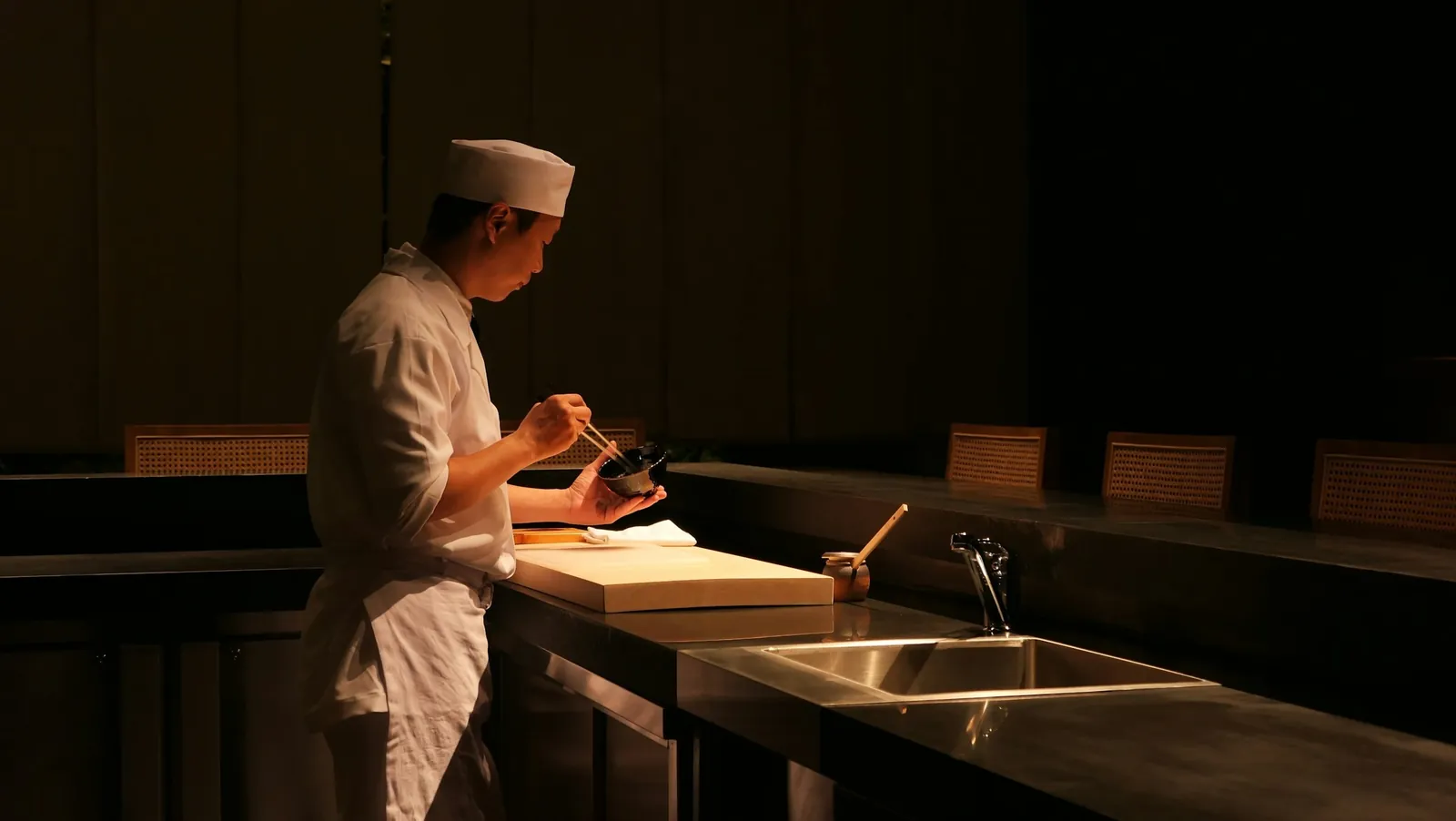 Chef alone at a dark sushi counter