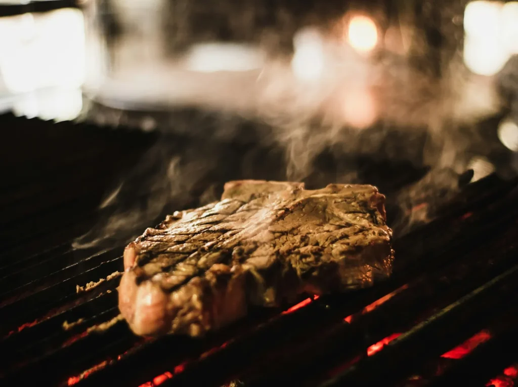 Steak on a hot grill in a dark kitchen