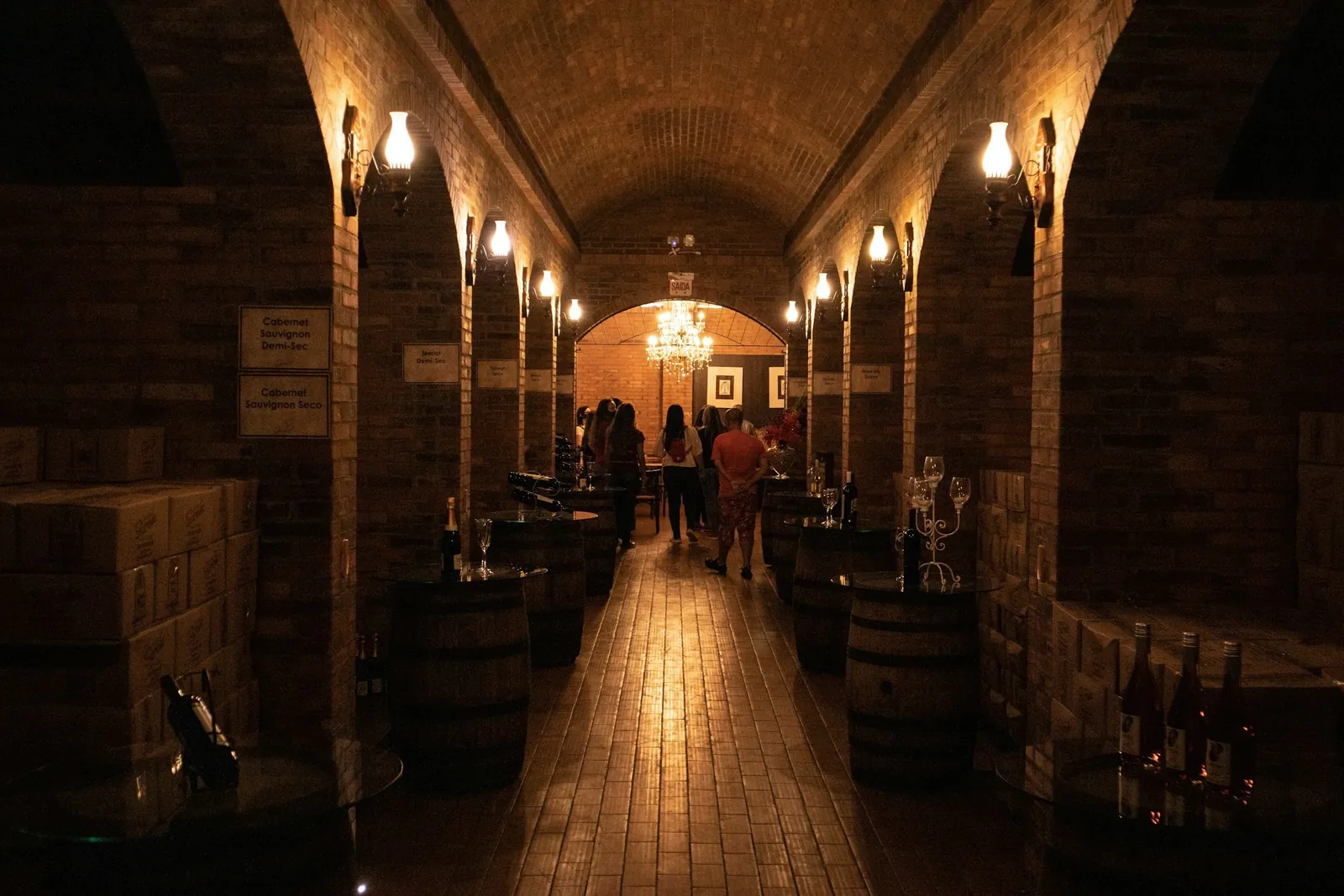 Arched brick wine cellar lit by sconces