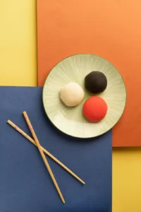 Three mochi on a plate with chopsticks
