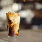 Iced coffee with condensed milk swirling in the glass