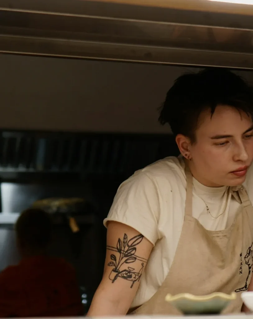 Cook plating bowls at the kitchen pass