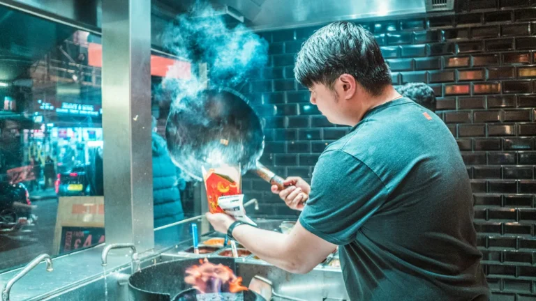 Cook tossing a wok over a high flame