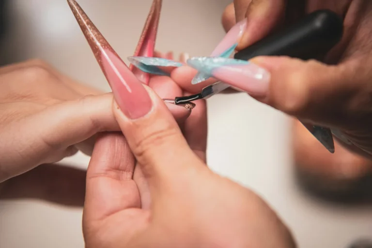Artist sculpting a long pink nail