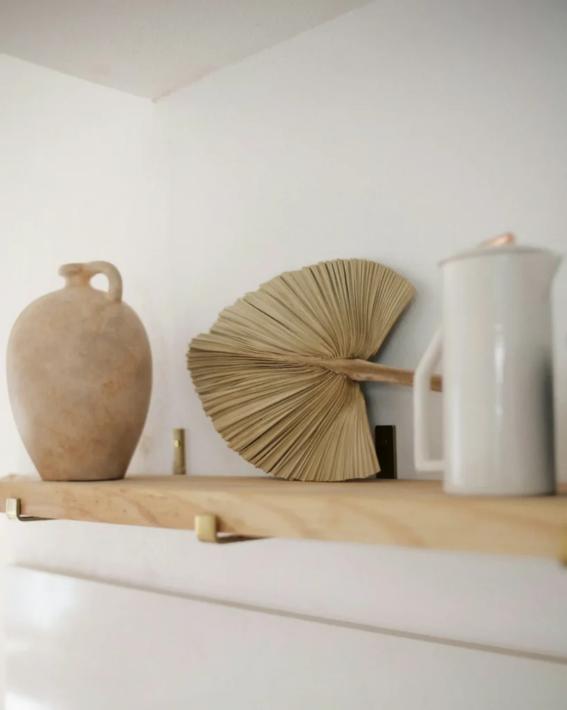 Clay vase and a palm leaf fan on a shelf