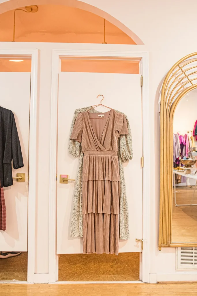 Blush dress on a hanger by an arched mirror