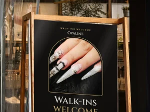 A wooden standing sign with a nail salon poster