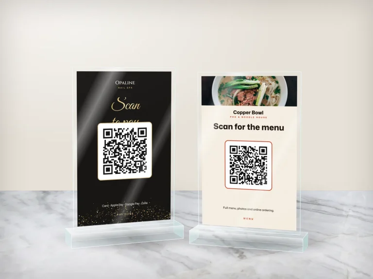 Two acrylic counter stands: a nail salon pay QR and a pho restaurant menu QR